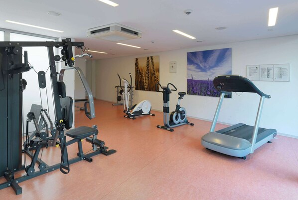 A gym with various exercise equipment including a treadmill, stationary bike, and weight machines. - Ramada by Wyndham Dresden (Dresden)