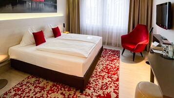 A hotel room with a large bed, a desk, a chair, a TV, and a painting on the wall.