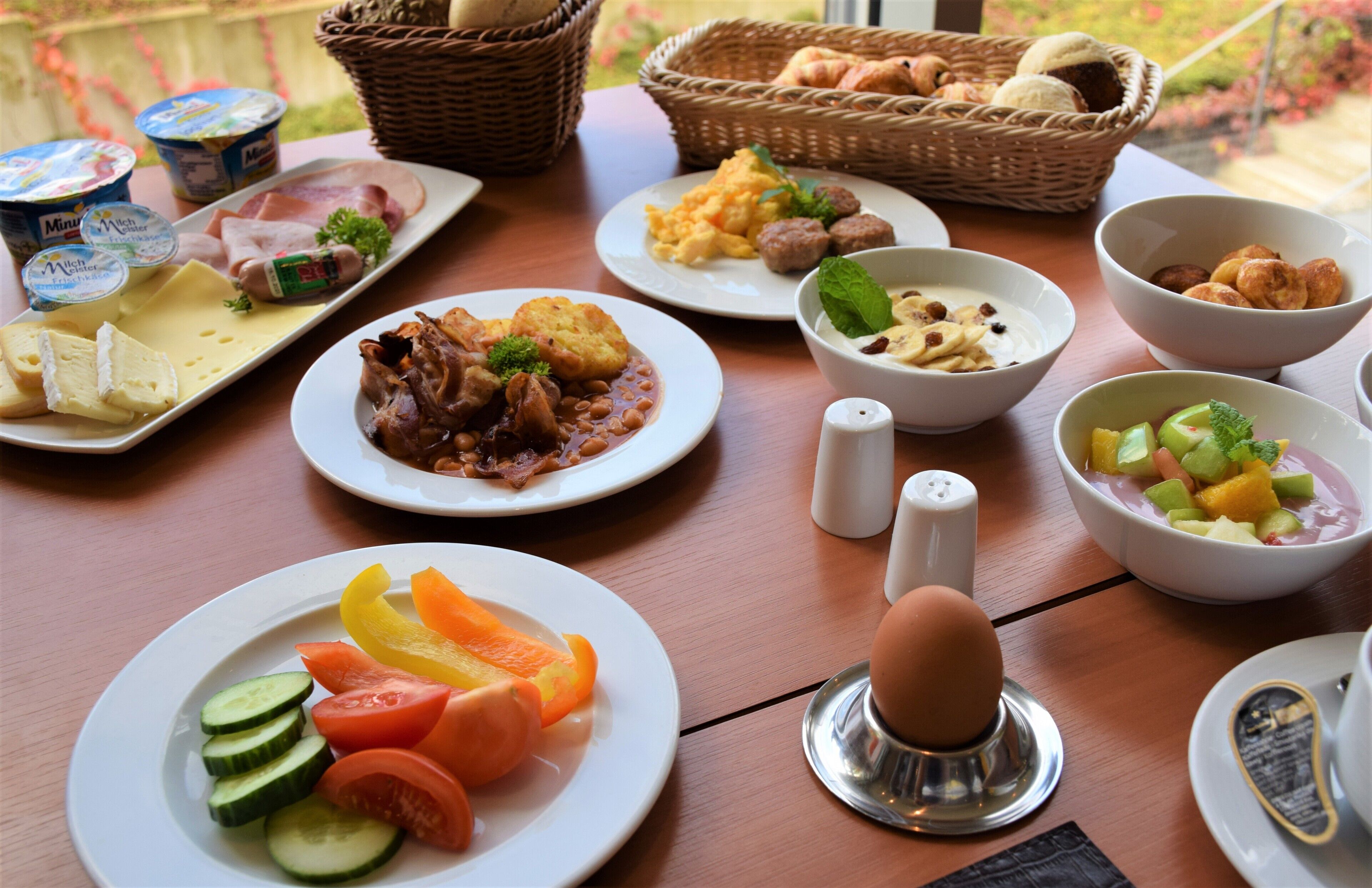 Una mesa de desayuno con diferentes platos, incluyendo huevos, verduras y pasteles.