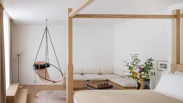 A modern bedroom with a hanging chair, a sofa bed, a chessboard, and a vase of flowers.