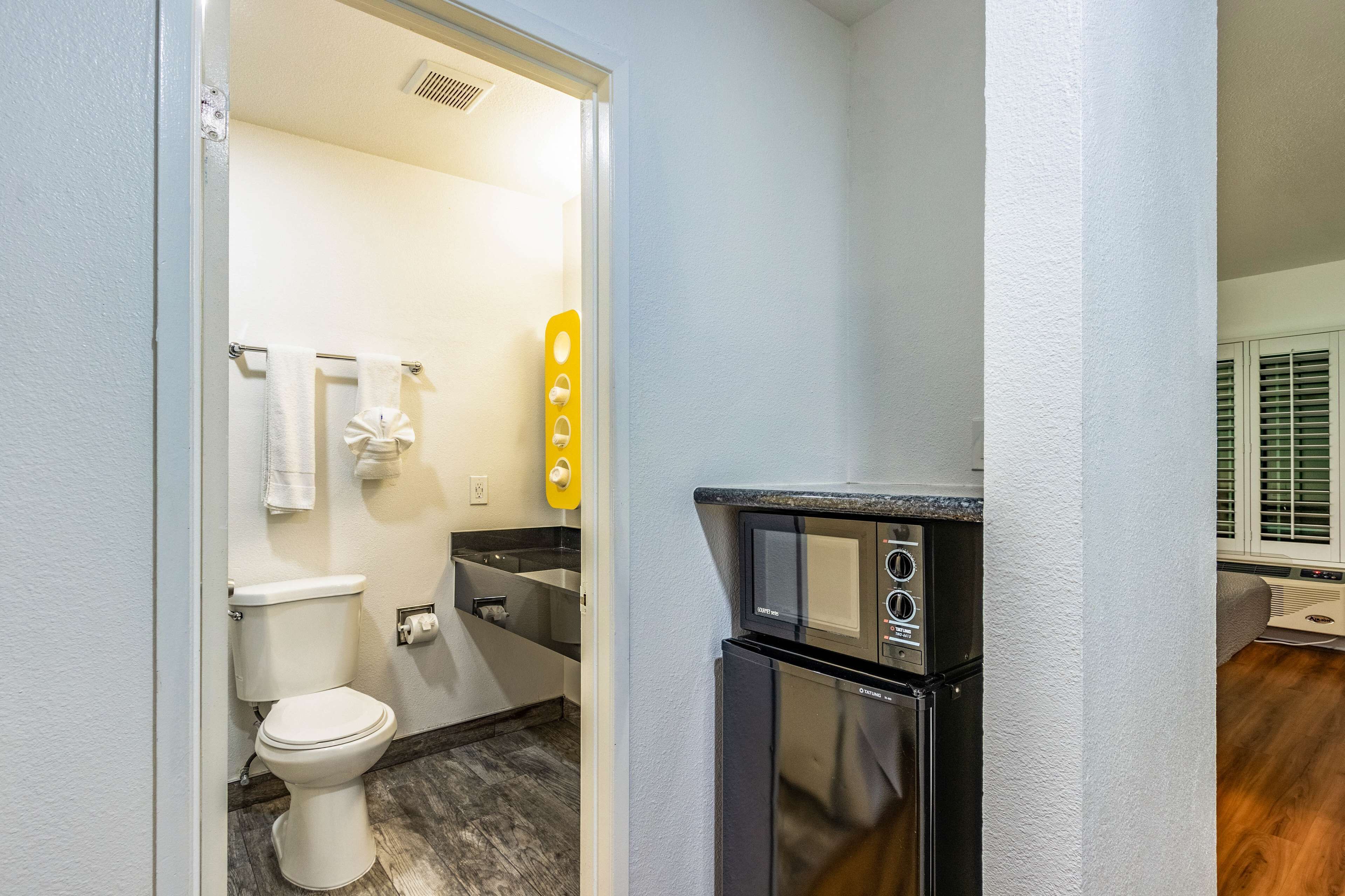 A compact bathroom with a toilet, sink, and a microwave.
