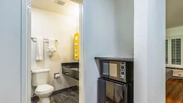 Un baño pequeño con inodoro, lavamanos y microondas.