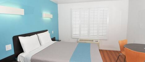 A modern hotel room with a bed, a desk, and a chair.