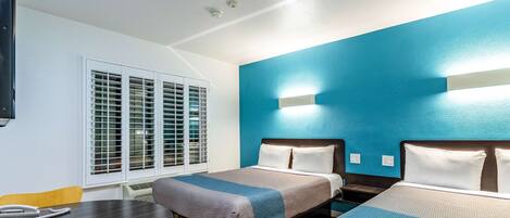 A hotel room with two beds, a desk, and a chair.