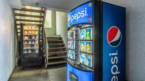 Máquinas expendedoras de Pepsi y de aperitivos en un estrecho pasillo con una escalera.