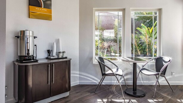Una cocina moderna con una cafetera, un mueble y dos sillas cerca de una ventana con vistas a zonas verdes.