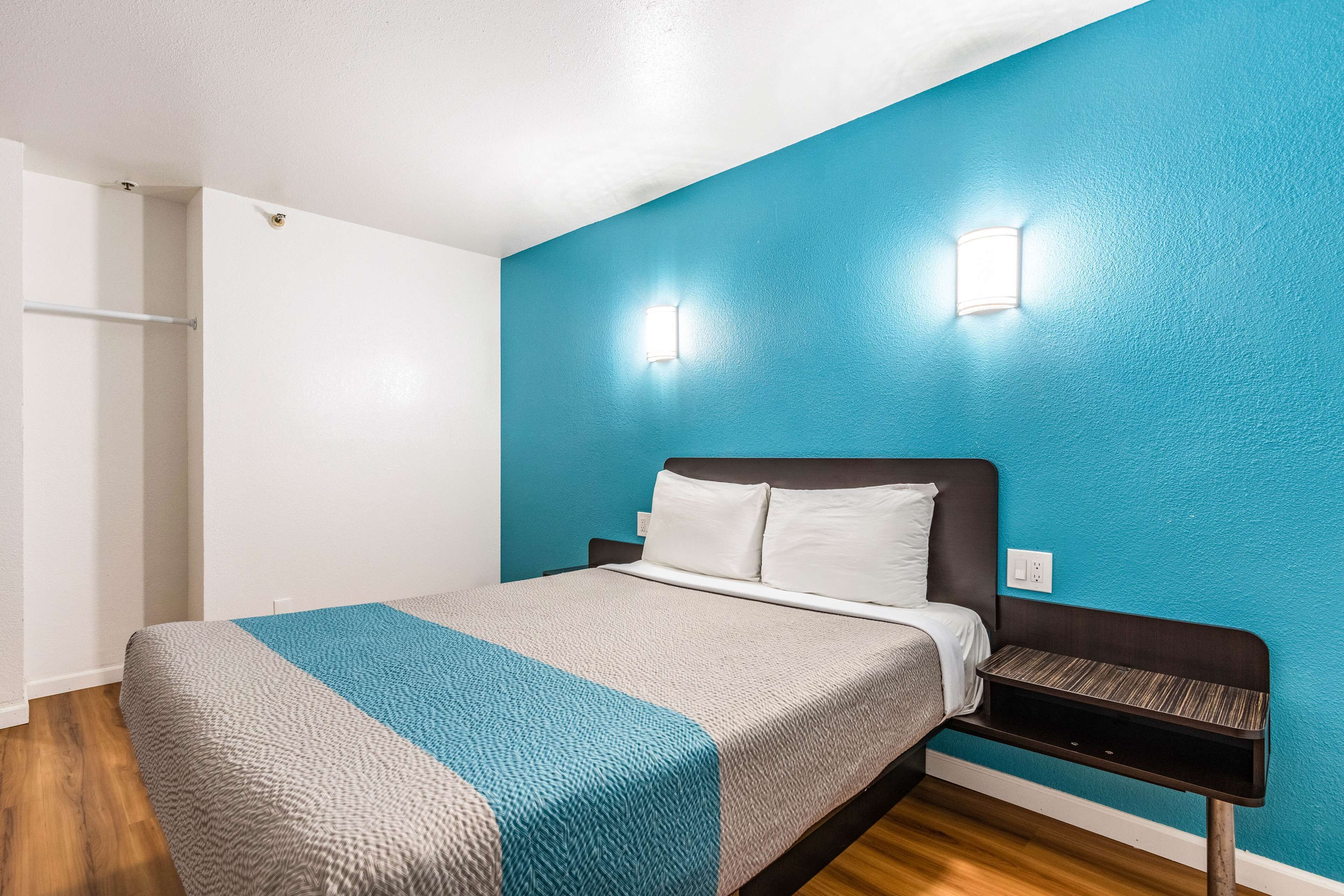 A bedroom with a bed, a nightstand, and a wall-mounted light fixture.
