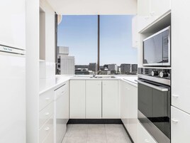 Una cocina moderna con armarios blancos, un lavamanos de acero inoxidable y un horno.