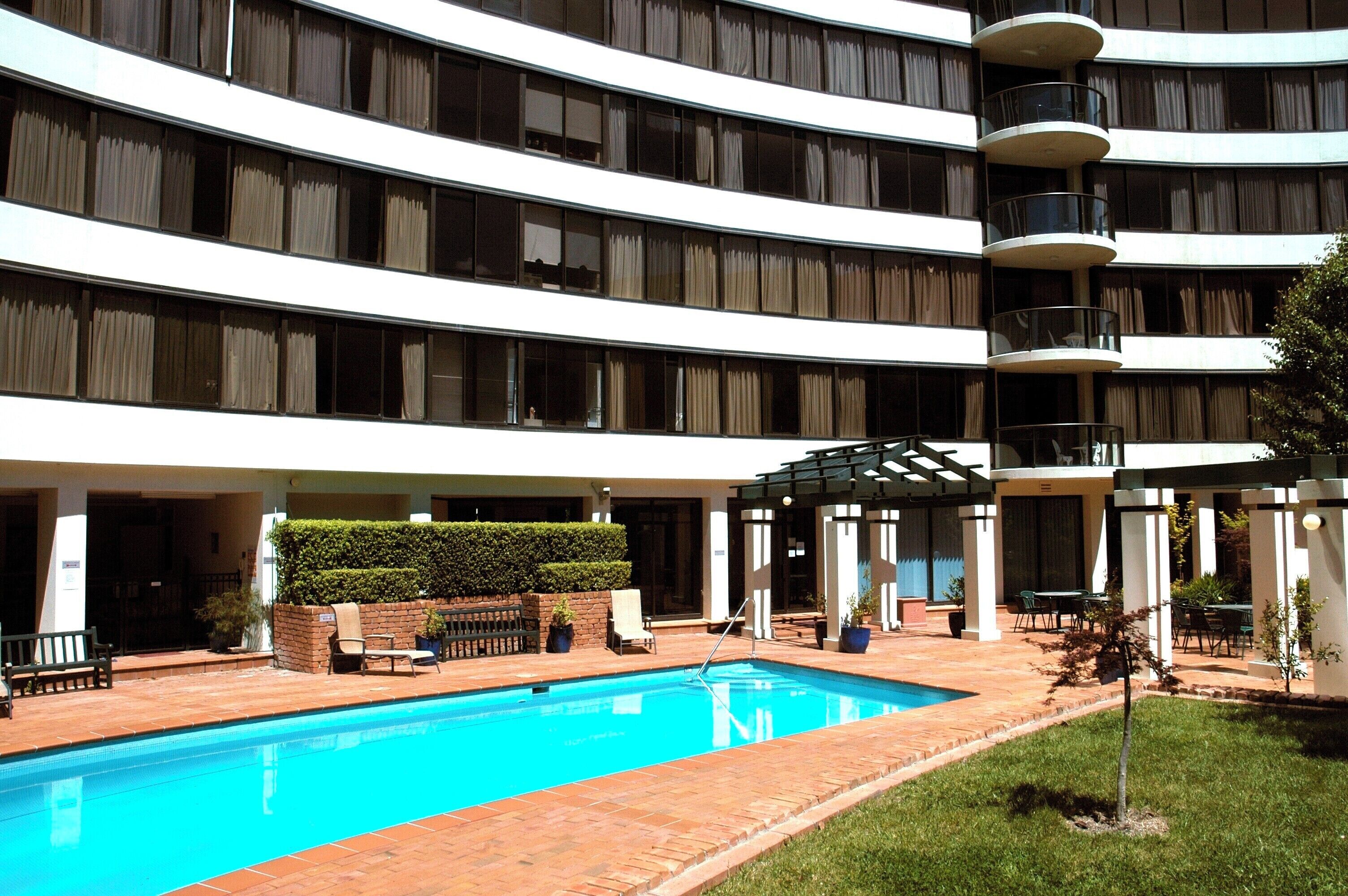 Un hotel de varios pisos con piscina, zona de estar al aire libre y un patio cubierto.