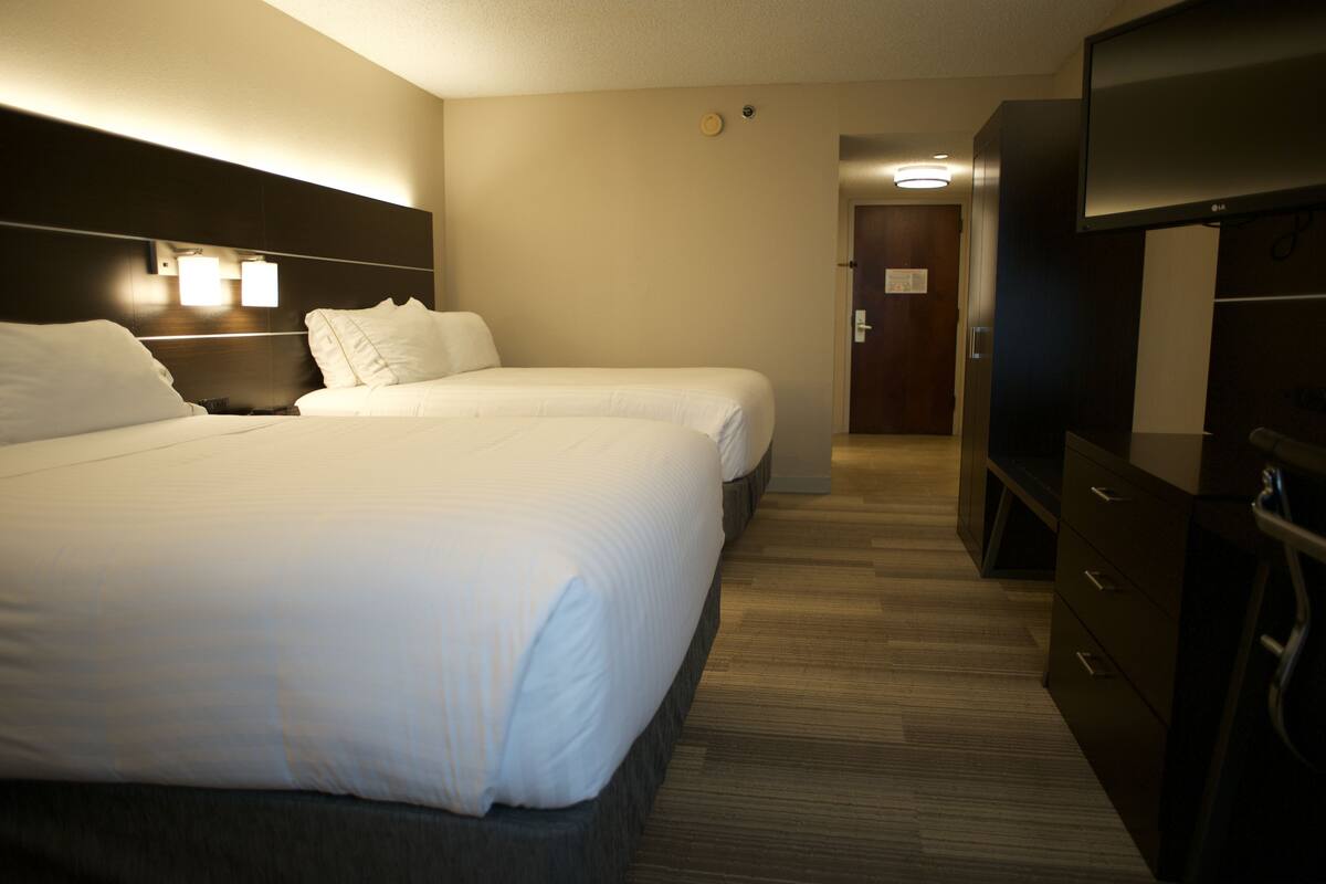 A hotel room with two beds, a TV, and a desk.