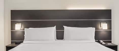 A hotel room with a large bed, two bedside tables, and wall-mounted lighting.