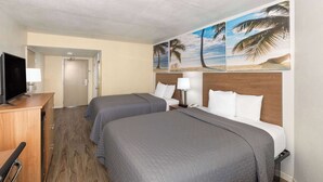 A hotel room with two beds, a TV, a desk, and a door leading to another room. - Days Inn by Wyndham Biloxi Beach (Biloxi)