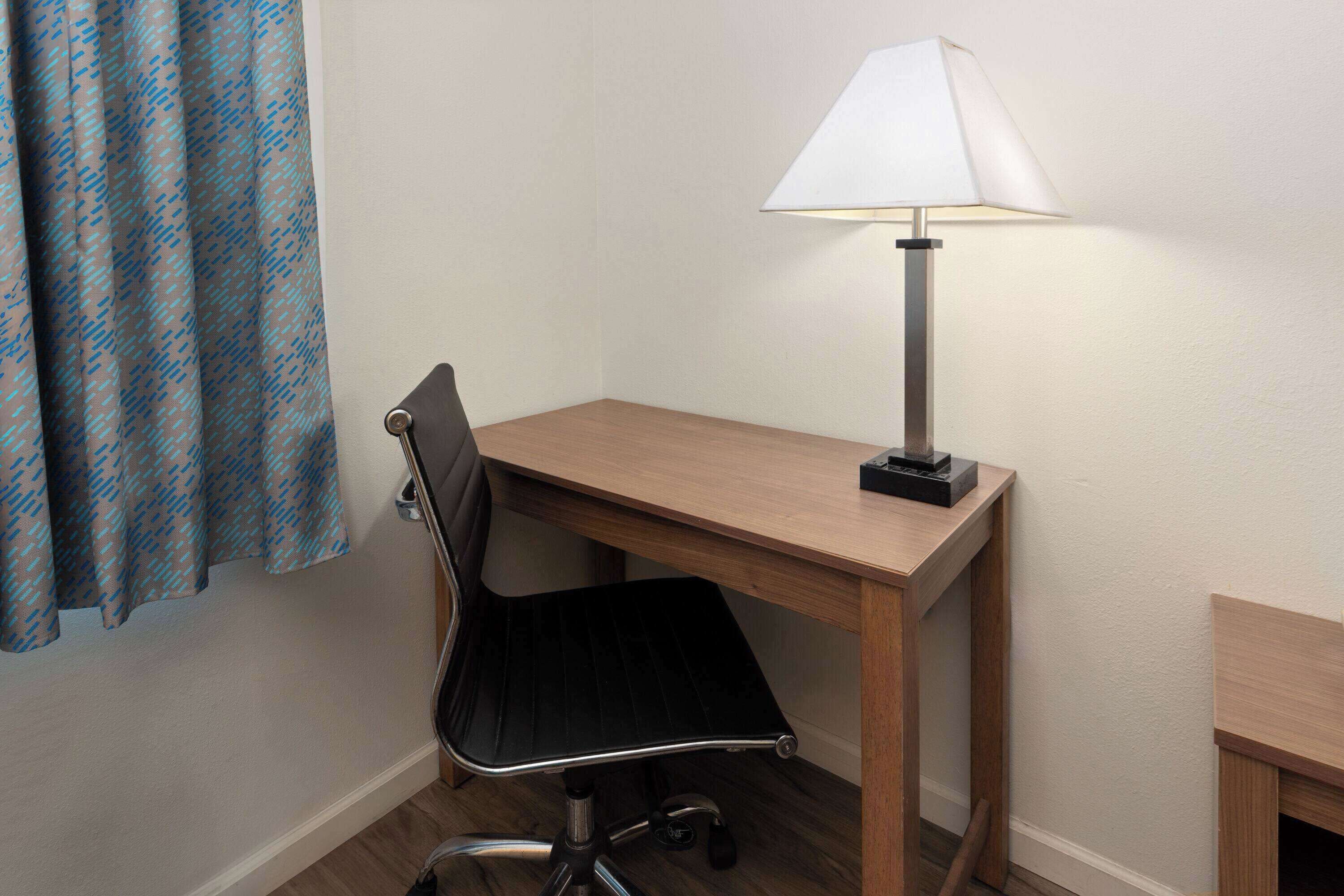 A small, neatly arranged workspace with a desk, chair, and a lamp.