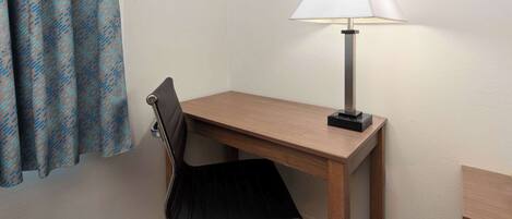 A small, neatly arranged workspace with a desk, chair, and a lamp.