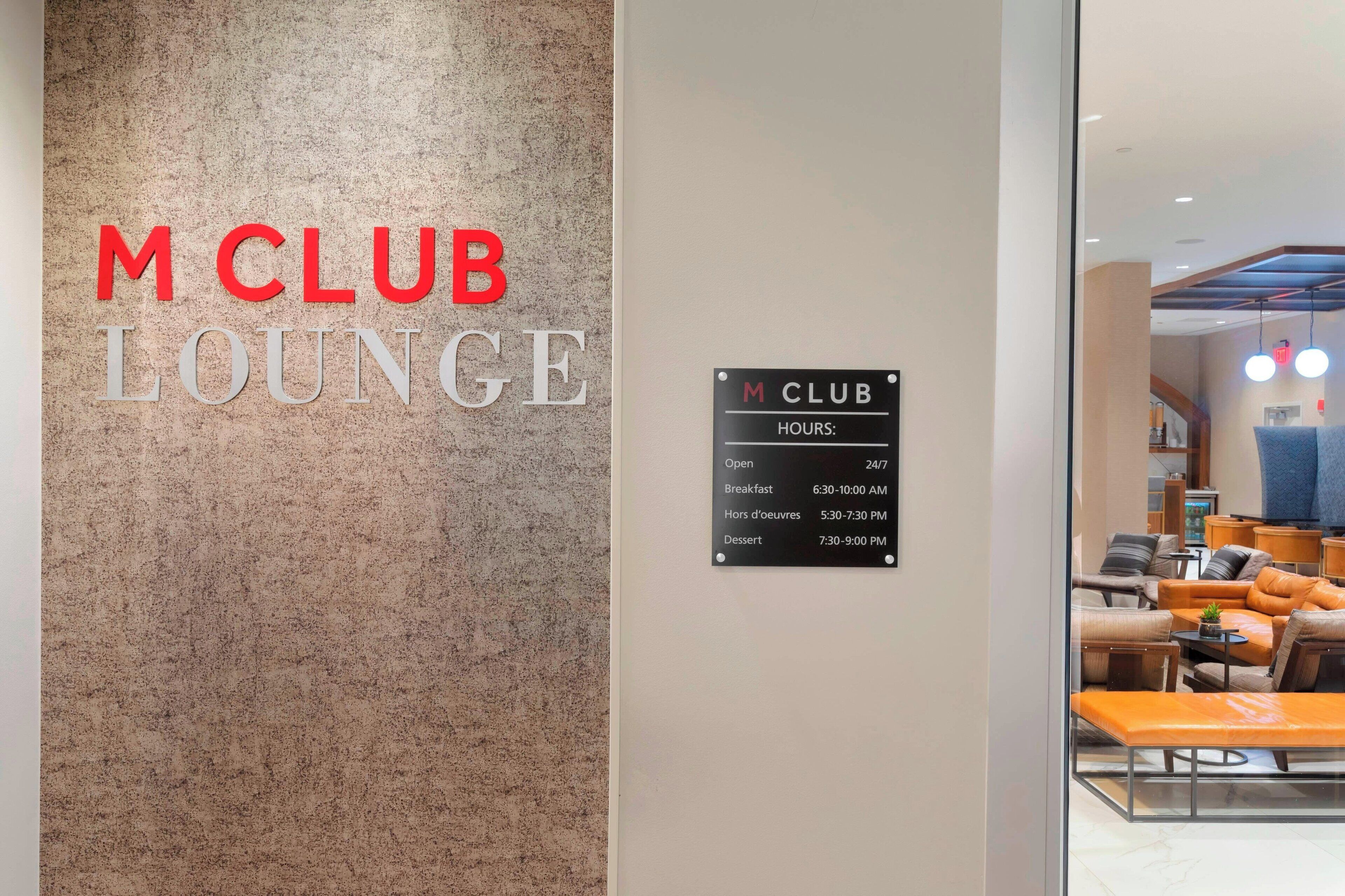 Schild für den M CLUB LOUNGE mit angezeigten Öffnungszeiten.
