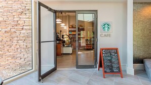 A modern interior with a stone wall, a glass door leading to a cafe, and a chalkboard menu outside. - Atlanta Marriott Northeast/Emory Area (Atlanta)
