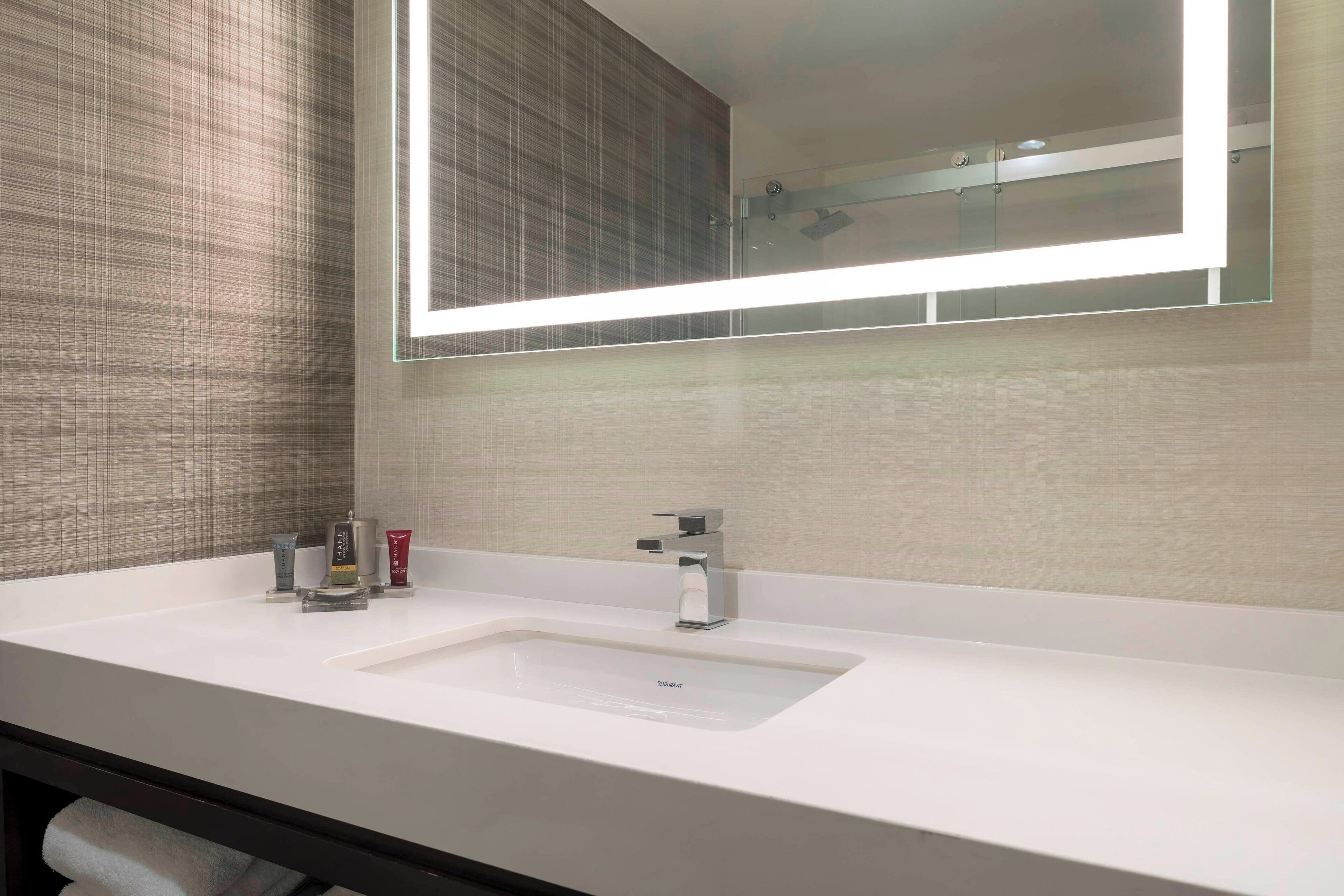 A modern bathroom with a white sink, a mirror, and a towel rack.