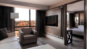 A modern hotel room with a large TV, a sofa, a chair, and a bed. - Atlanta Marriott Northeast/Emory Area (Atlanta)