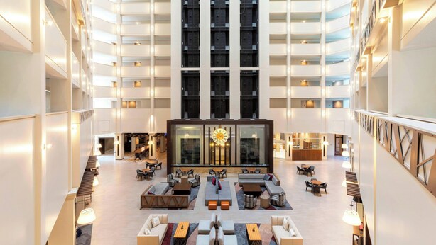 A spacious lobby with a central seating area, multiple floors, and a prominent clock. - Atlanta Marriott Northeast/Emory Area (Atlanta)