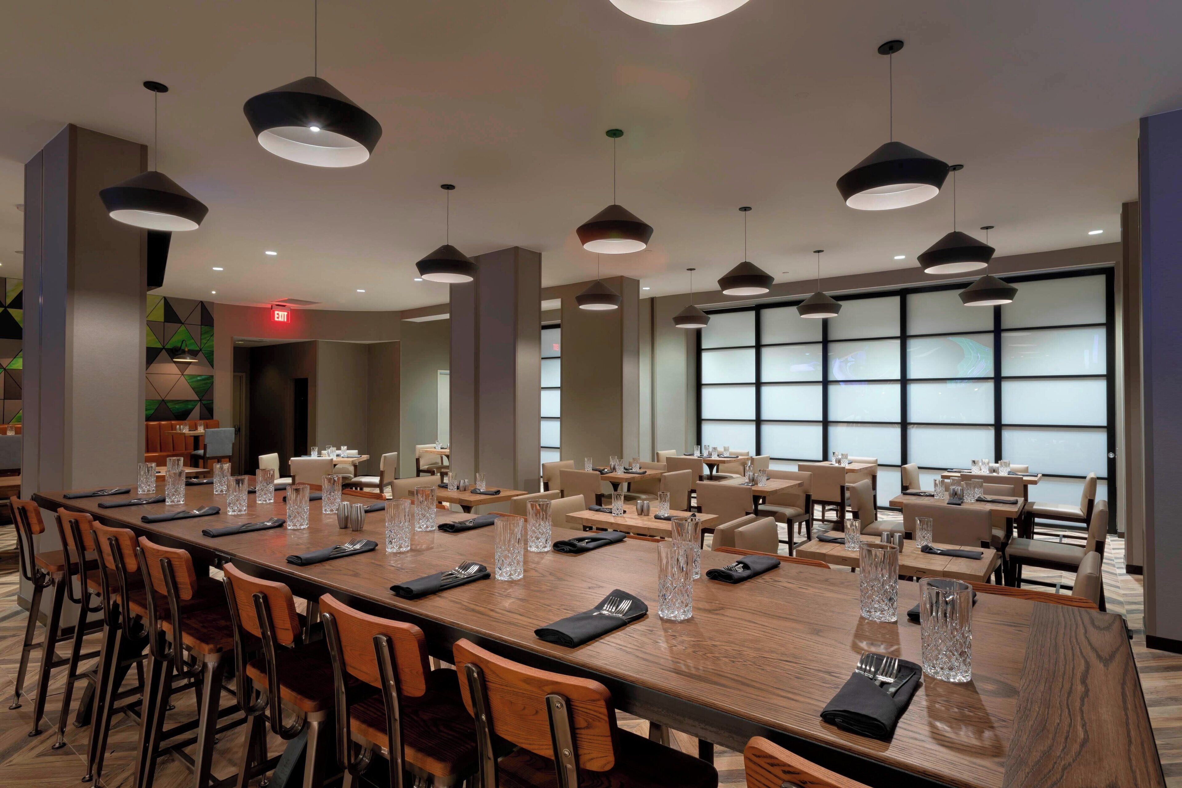 A spacious conference room with a long wooden table, multiple chairs, and pendant lighting.