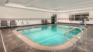 A swimming pool with a tiled deck, a changing room, and a seating area with chairs. - City Express By Marriott Lafayette (Lafayette)