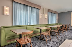 Una habitación de hotel con un sofá verde, mesas y sillas de madera.