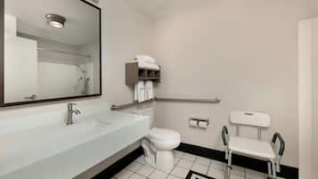 Une salle de bain moderne avec un lavabo blanc, des toilettes, un miroir et une barre d’appui.