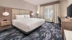 A hotel room with a large bed, bedside tables, a desk, and a chair. - City Express By Marriott Lafayette (Lafayette)