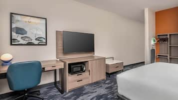 Ein Hotelzimmer mit Bett, Schreibtisch, Flachbildfernseher, Stuhl, Mikrowelle und Kleiderschrank.