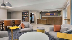 A hotel lobby with seating areas, a reception desk, and a minibar. - City Express By Marriott Lafayette (Lafayette)
