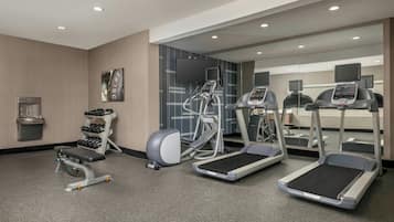 A gym with treadmills, an elliptical, a bench, and a dumbbell rack.