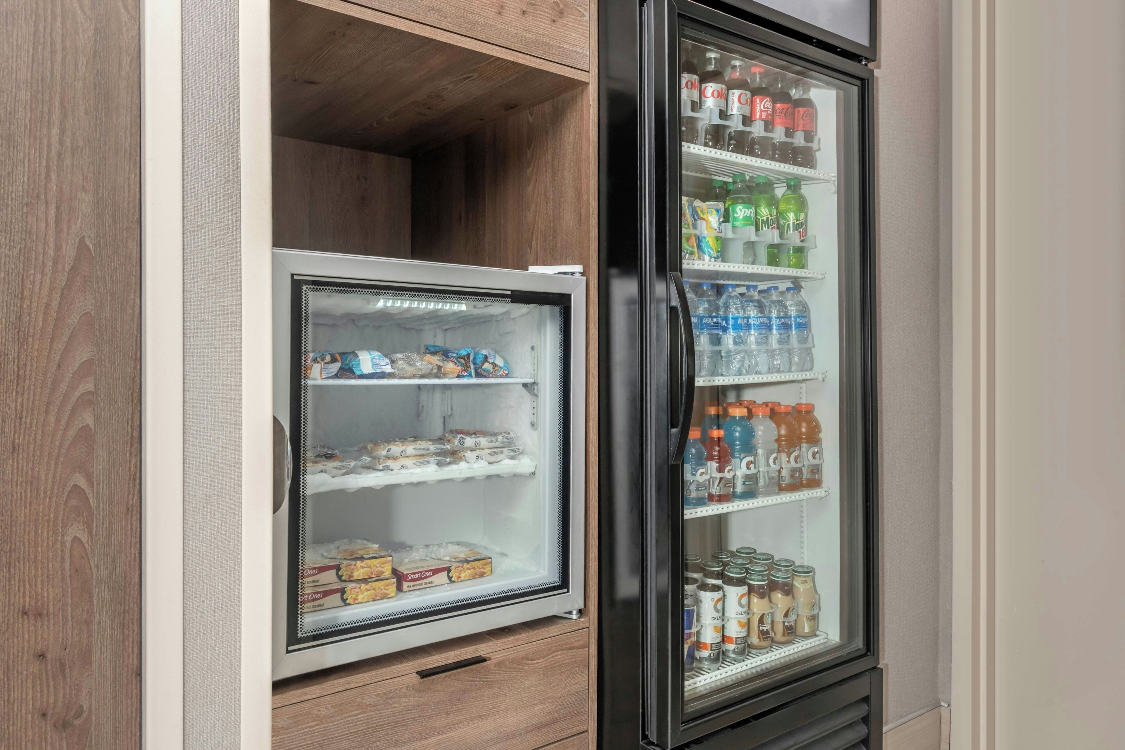 A refrigerator stocked with beverages and snacks, including bottled water, soda, and boxed food items.
