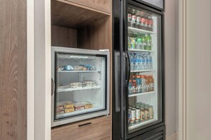 A refrigerator stocked with beverages and snacks, including bottled water, soda, and boxed food items.