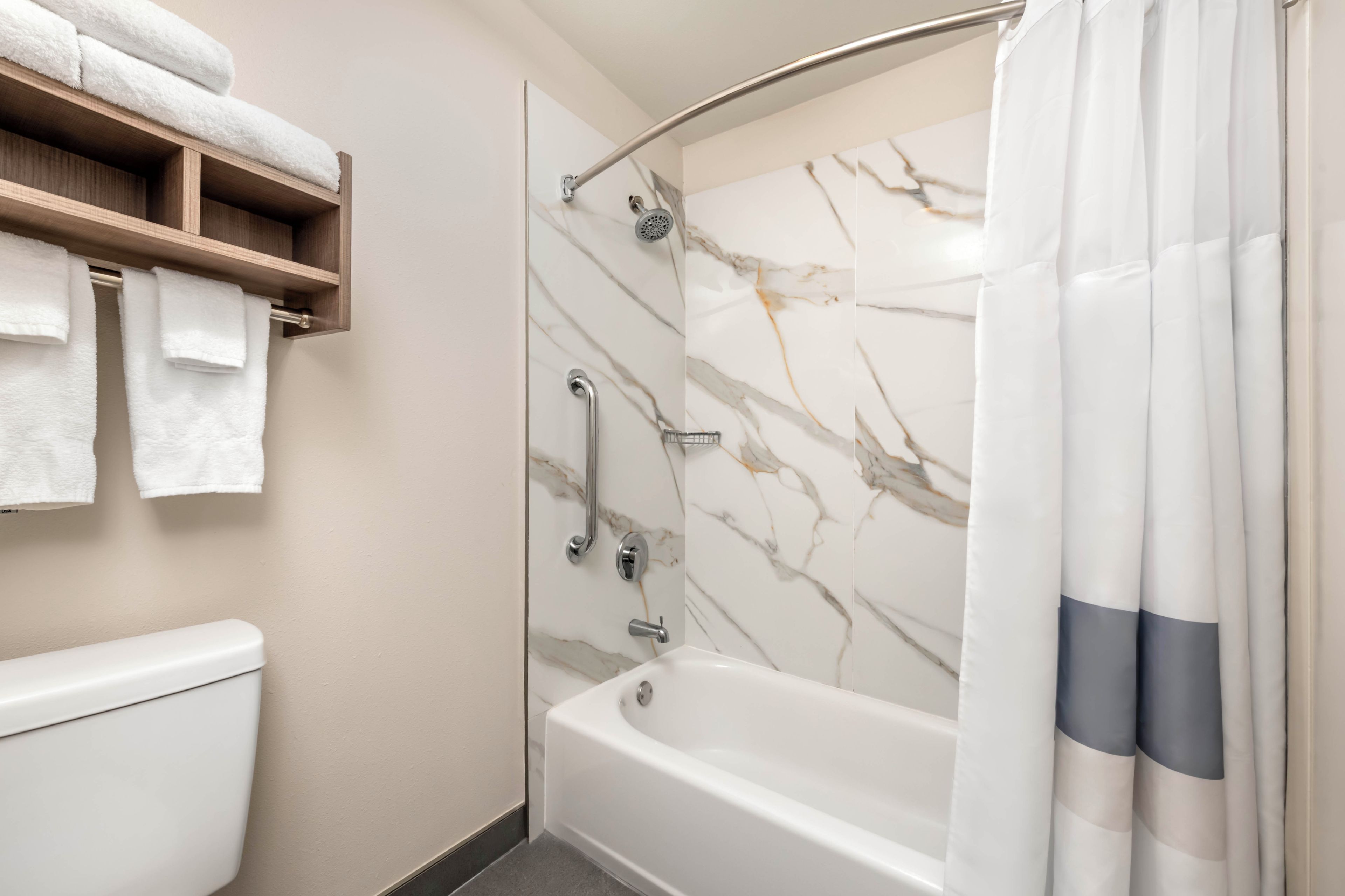 A bathroom with a shower, toilet, and a towel rack.
