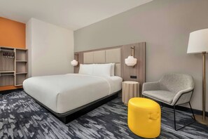 A hotel room with a large bed, a bedside table, a chair, a lamp, and a wardrobe. - City Express By Marriott Lafayette (Lafayette)