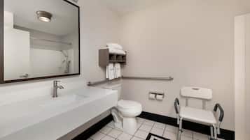 Une salle de bain moderne avec un lavabo blanc, des toilettes, un miroir et une barre d’appui.