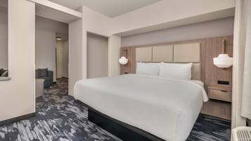 A hotel room with a large bed, bedside tables, a desk, and a chair.
