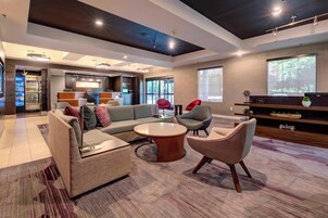 A modern living room with a sofa, chairs, a coffee table, and a kitchen area in the background.