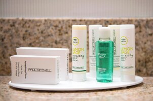Variedad de productos para el cuidado de la piel Paul Mitchell, incluyendo loción corporal, gel de baño y enjuague bucal, sobre una encimera.