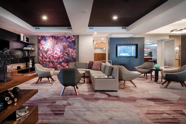 A modern living room with a sectional sofa, armchairs, a coffee table, and a large floral mural.