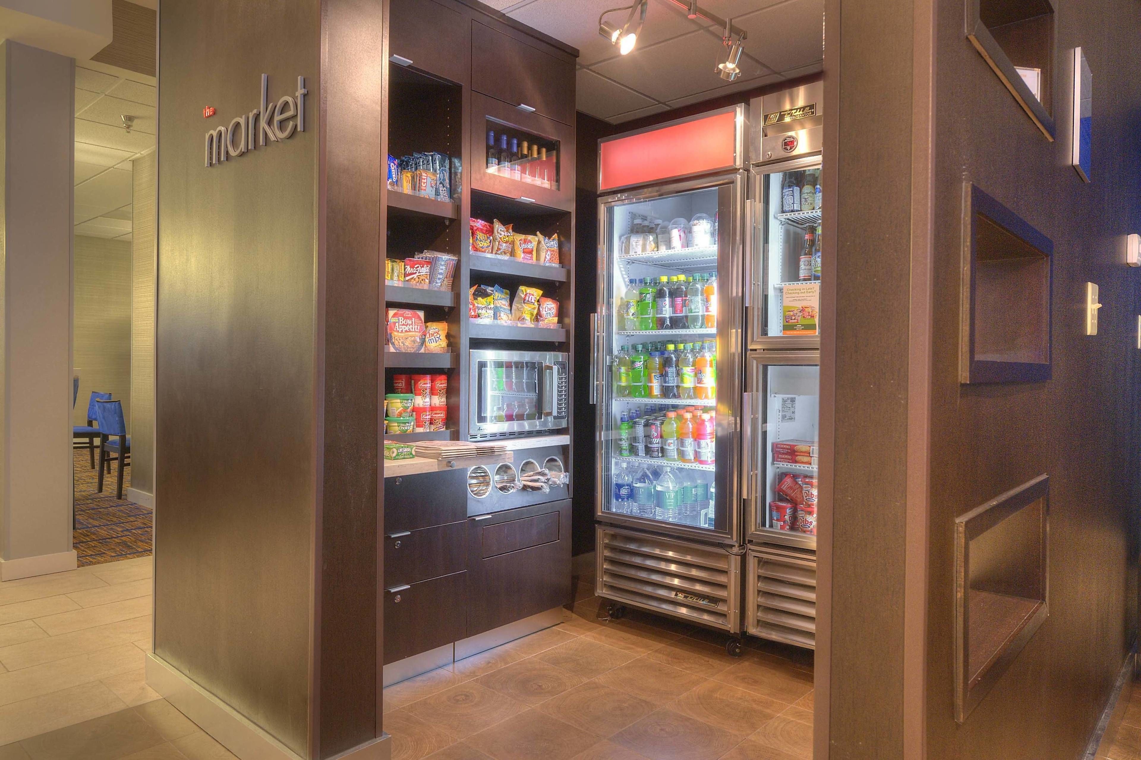 A vending area with snacks, a microwave, and a refrigerator stocked with beverages.