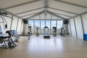 A gym with various exercise equipment, large windows, and a high ceiling. - Eurostars Hotel Real (Santander)