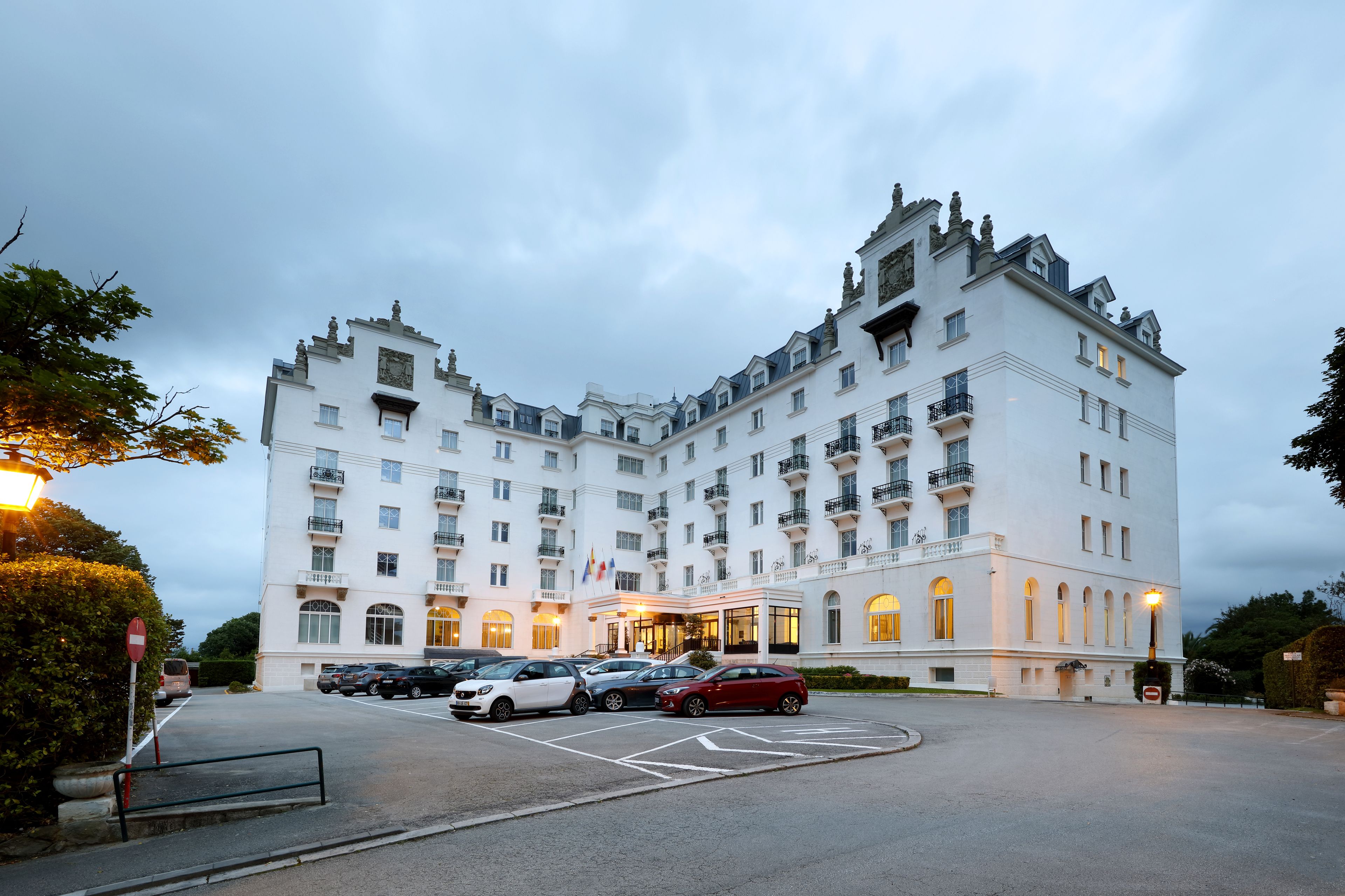Un hotel grande y blanco de varios pisos con un estilo arquitectónico europeo clásico, que cuenta con balcones y una entrada central.