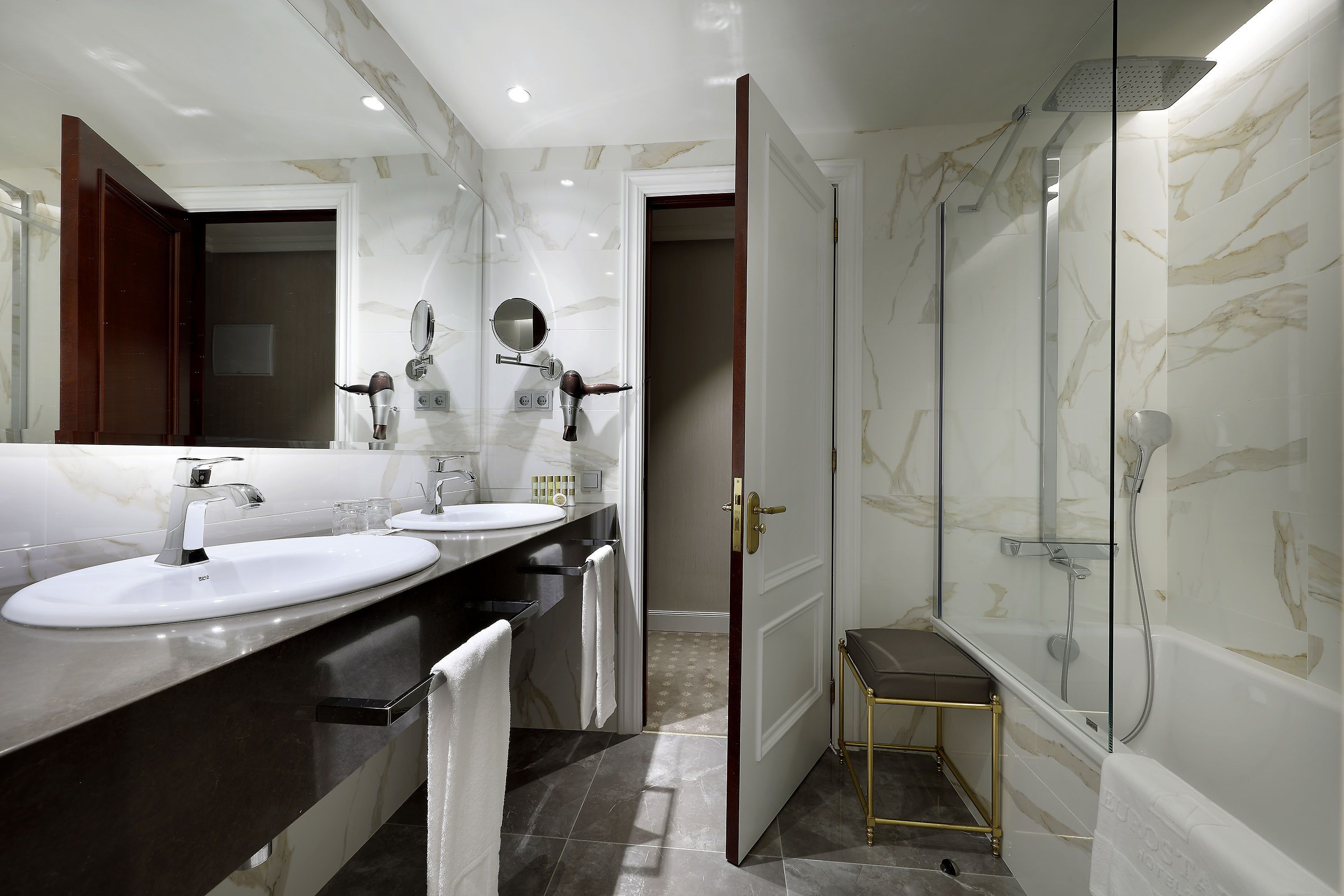 Un baño moderno con dos lavamanos, un espejo, un secador de pelo y una zona de ducha.