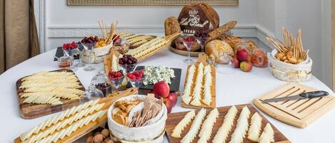 Una mesa con varios quesos, frutas y pan, dispuesta para un bufé.