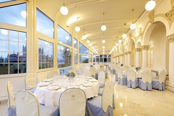 A banquet hall with round tables set for dining, large windows, and classical architecture. - Eurostars Hotel Real (Santander)