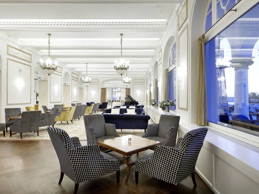 A spacious lobby with patterned chairs, a central table, and chandeliers.