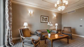 A room with a wooden coffee table, two armchairs, a sofa, and a chandelier.