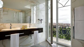 A modern bathroom with a dual sink vanity, a large mirror, and a view of a balcony with a railing.