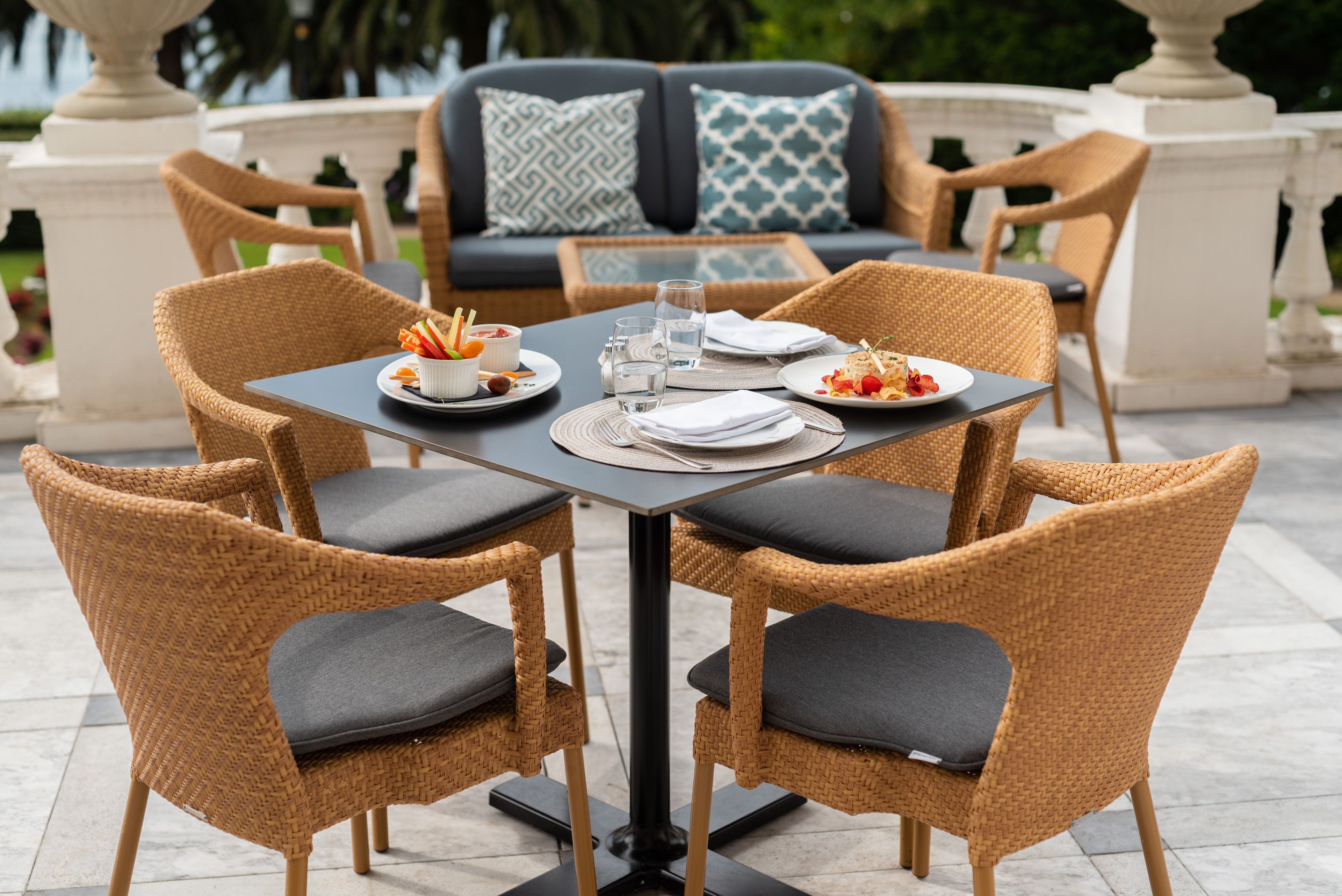 A dining area with wicker chairs and a table set for four.